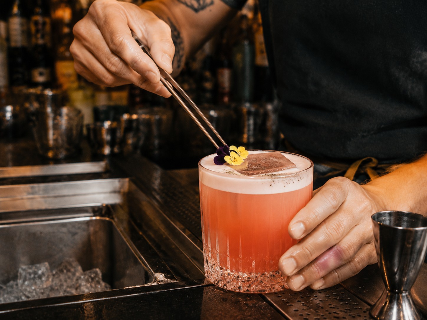 Barman déposant une fleur sur un cocktail à la pince