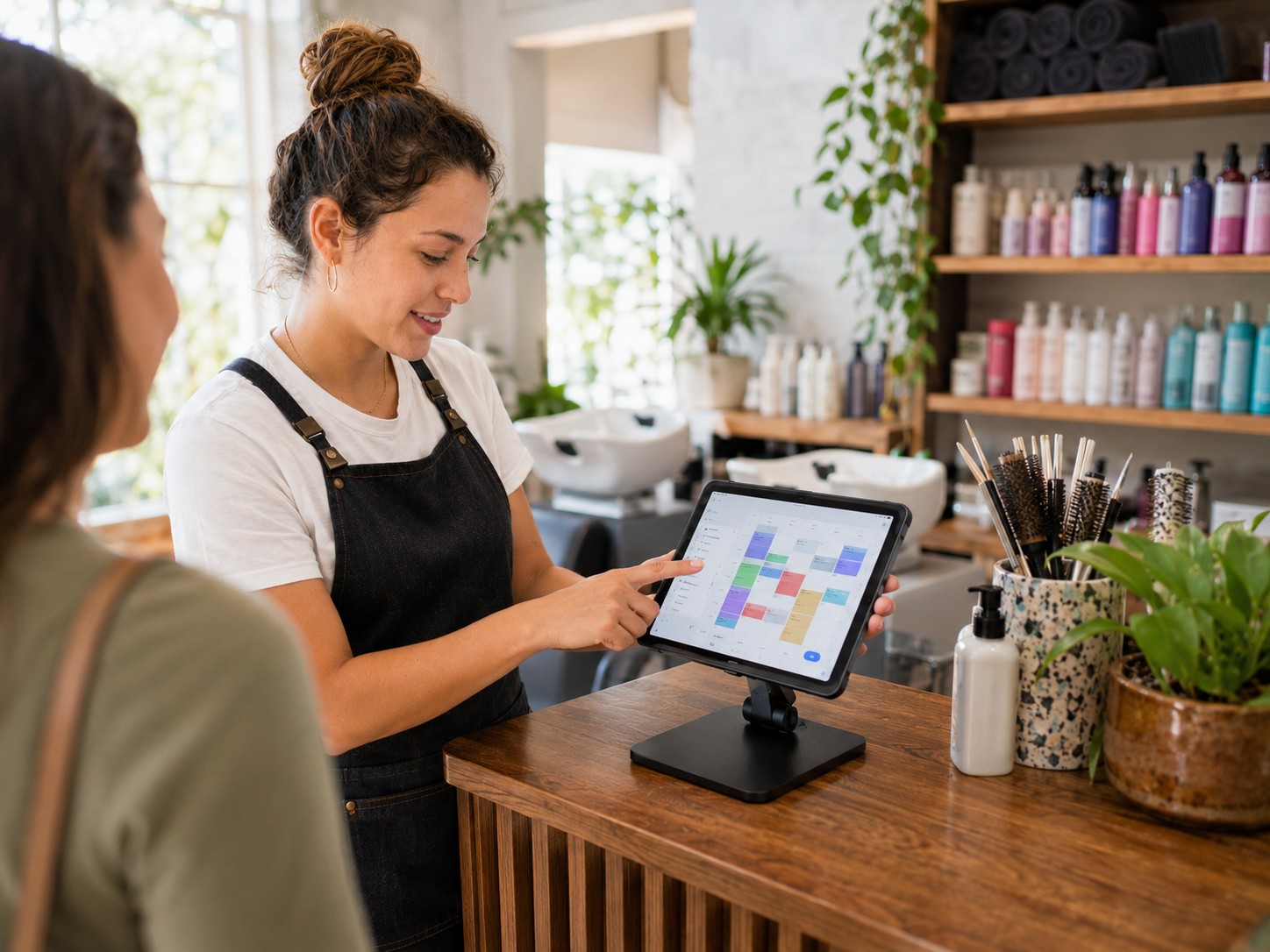 Coiffeuse montrant le planning sur tablette à une cliente